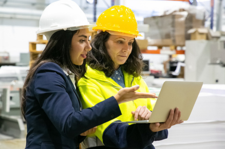 Female manufacturing workers looking at laptop